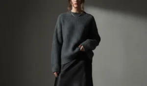 Cozy luxury aesthetic: woman in a chunky charcoal knit sweater and black silk midi skirt.