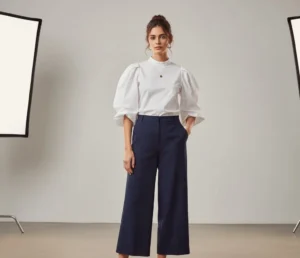 Creative office style: woman in a white puff-sleeve blouse and navy blue culottes.
