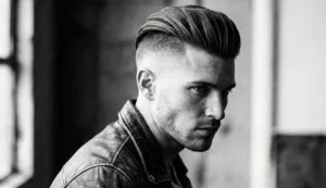 A black and white side profile photograph of a man with a sleek, high-volume slicked-back undercut hairstyle and neatly shaved sides.