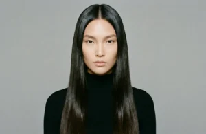 Frontal symmetrical portrait of an Asian woman with long, bone-straight dark hair with a high-shine 'glass hair' finish, parted in the center.