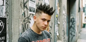 An edgy portrait of a teenager leaning against a graffiti wall, featuring tall liberty spikes and shaved sides, wearing an Iron Maiden t-shirt.