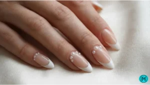 Elegant French tip nails with small pearl accents near cuticles.