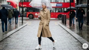 11 Trench Coat & Leggings Practical spring outfit for rainy weather featuring a tan trench coat, black leggings, and white sneakers.