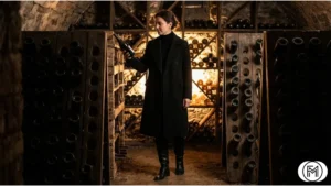 Classic all-black winter ensemble with a wool coat and leather boots in a wine cellar.