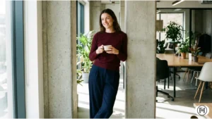 Navy relaxed-fit trousers with a burgundy fine-gauge sweater for a simple winter work look.