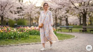 2 Floral Dress & Sneakers A woman in a flowy pastel floral midi dress paired with white leather sneakers walking in a spring park.