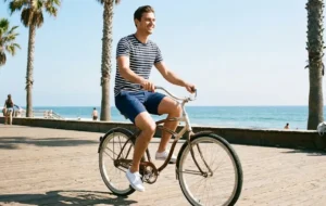 Man on a bicycle wearing a striped t-shirt and shorts, a classic summer casual look.