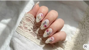 7. Milk Bath Nails Alt Text: Milky white nails with embedded dried flowers and gold flakes, known as the Milk Bath trend. 