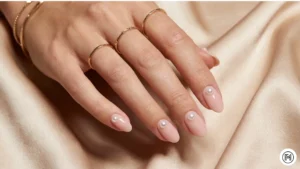 9. Built-In Pearl Accents Alt Text: Nude nails featuring elegant 3D pearl accents for a luxury summer manicure. 