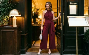 A woman in a burgundy jumpsuit stands smiling in the doorway of a restaurant called "Bistro".