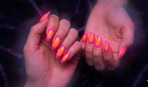 An editorial-style aura nail design showing an airbrushed blend of hot neon pink radiating into a glowing neon orange center.