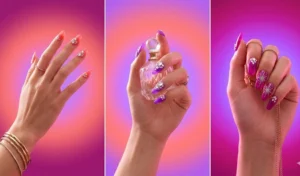 Professional manicure showing a seamless radial airbrush aura gradient in sunset hues of magenta, coral, and violet with delicate metallic starburst nail art.