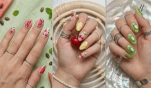 A playful summer manicure with hand-painted fruit illustrations, including watermelon, lemon, and cherry slices on a clear, milky nail base.