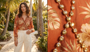 Gold rhinestone body chain layered over a sheer burnt-orange tropical print blouse.